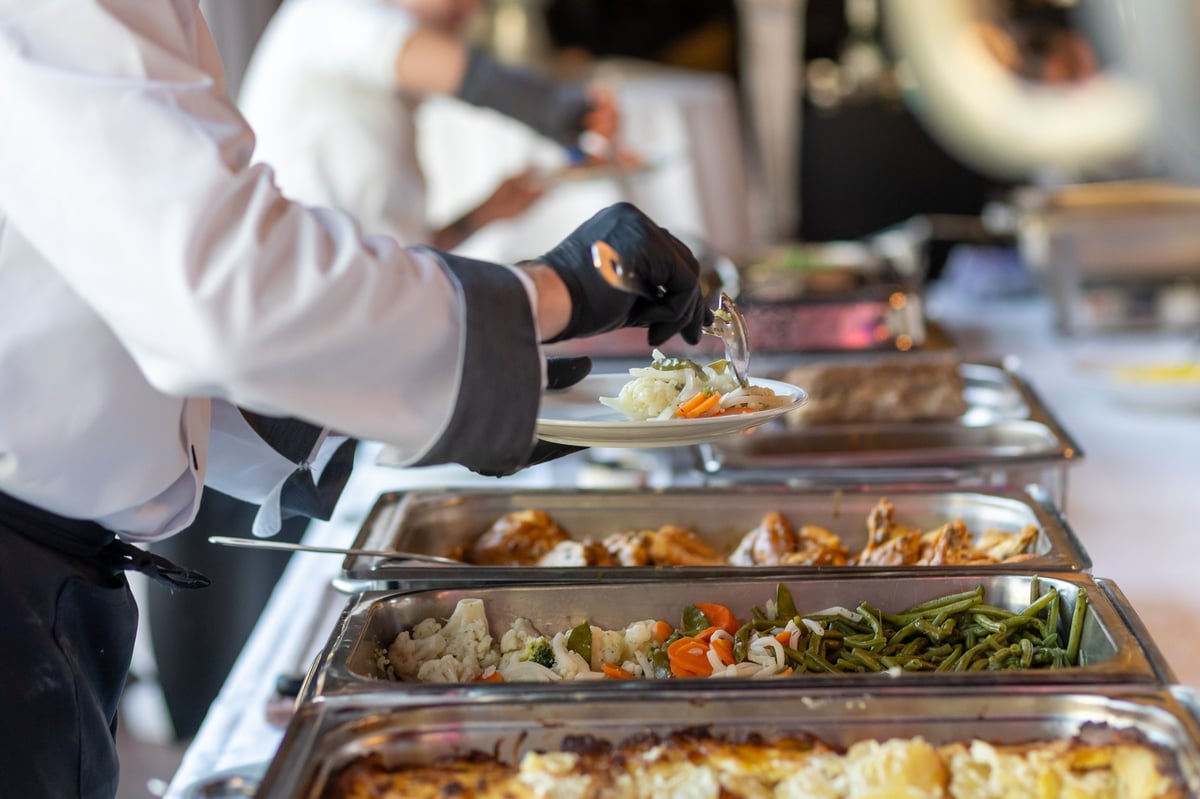Elegant catered event in a spacious hall with staff serving gourmet dishes
