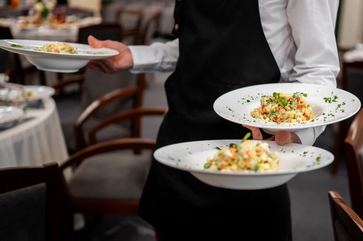 Professional waiter serving colorful plated meals
