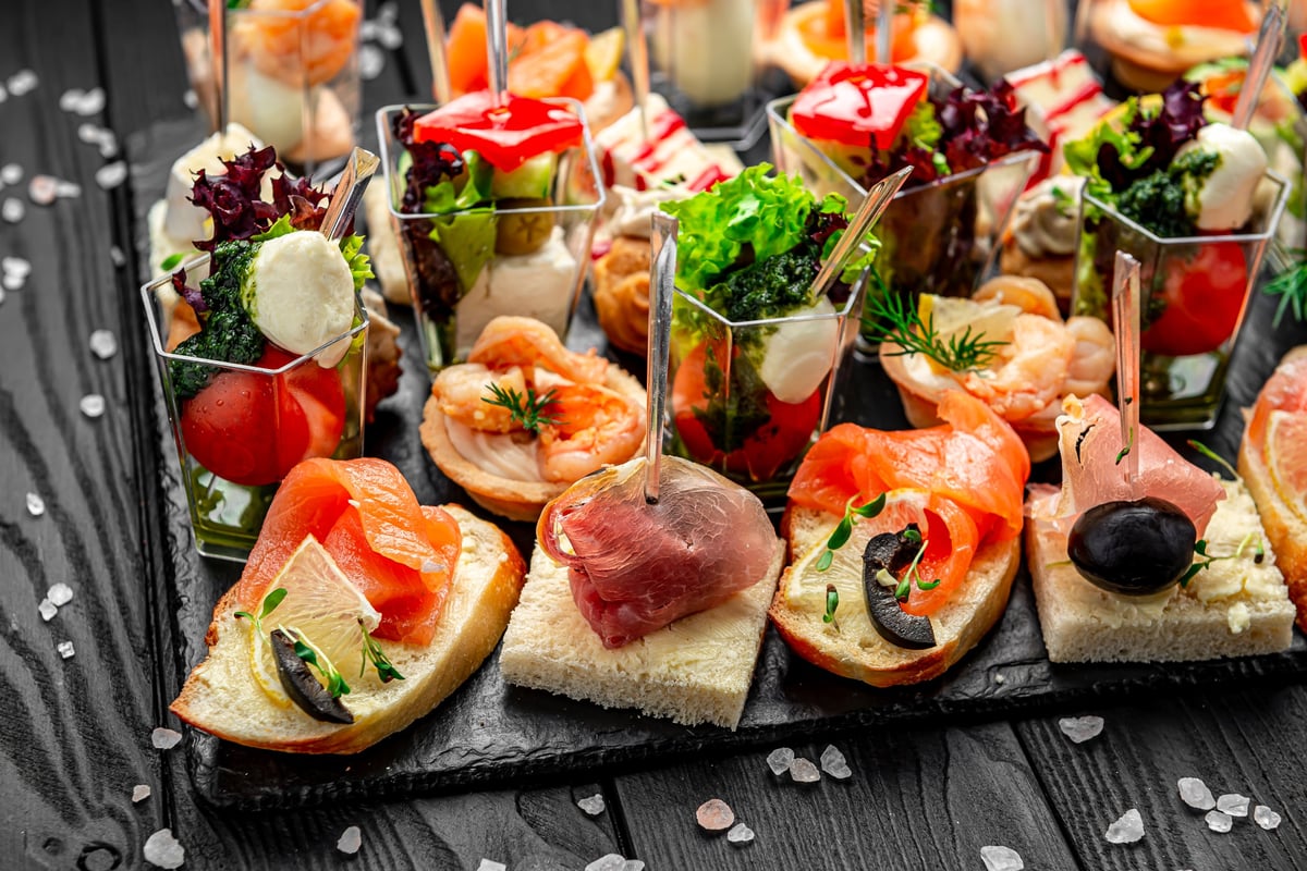 Assorted appetizers served on a black tray at an evening event